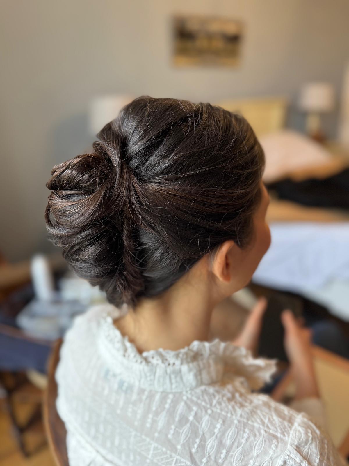 Chignon flou torsadé sur cheveux bruns, mise en beauté de mariée